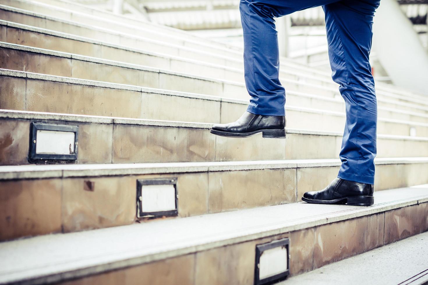 Close-up of young businessman walking upstairs outside office photo