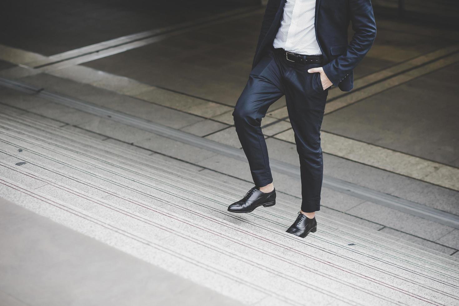 Close-up of young businessman walking upstairs outside office photo