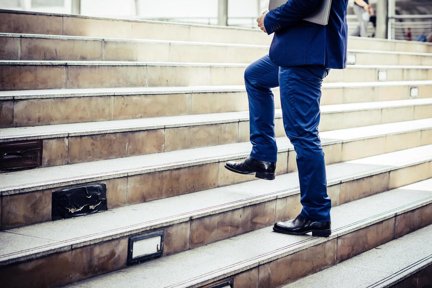 Close-up of young businessman walking upstairs outside office photo