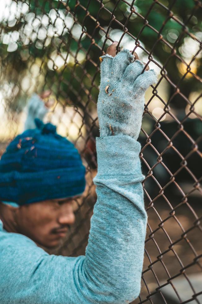 Beggars that wear to hands and stick to a metal grating photo