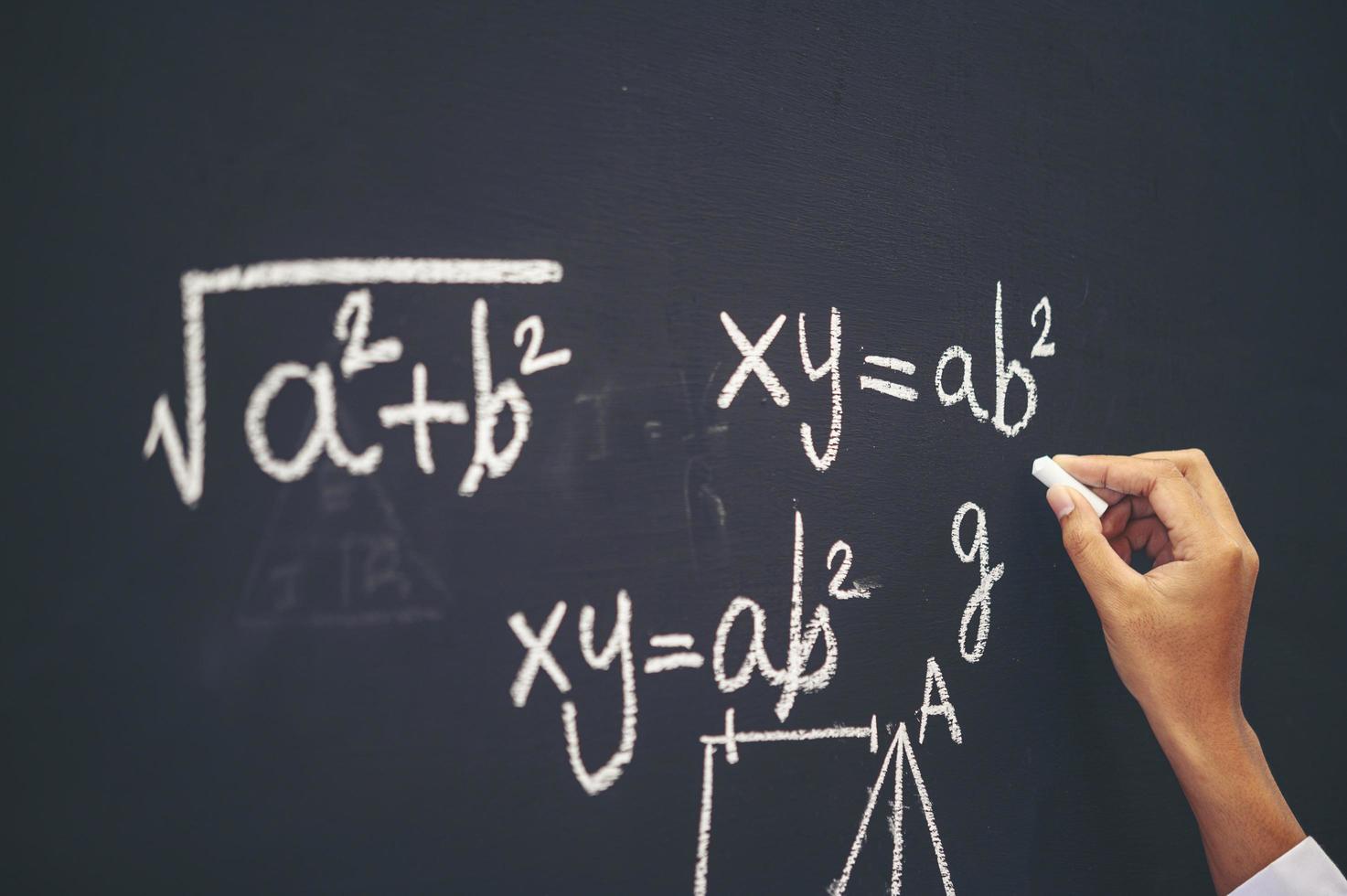 Student writes the formula with white chalk on the blackboard photo