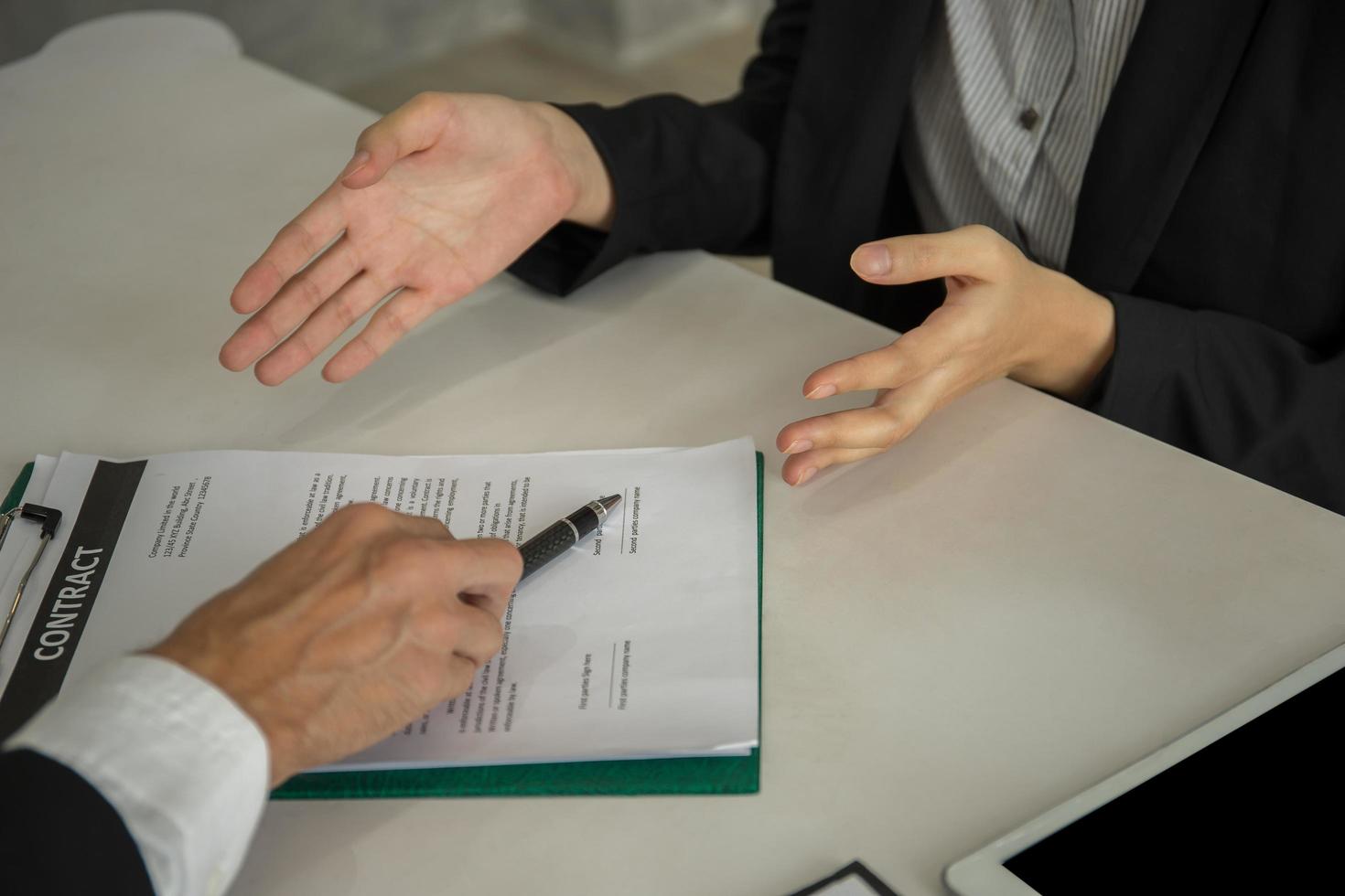 Gente de negocios sentada en el escritorio apuntando al documento para la firma despedida foto