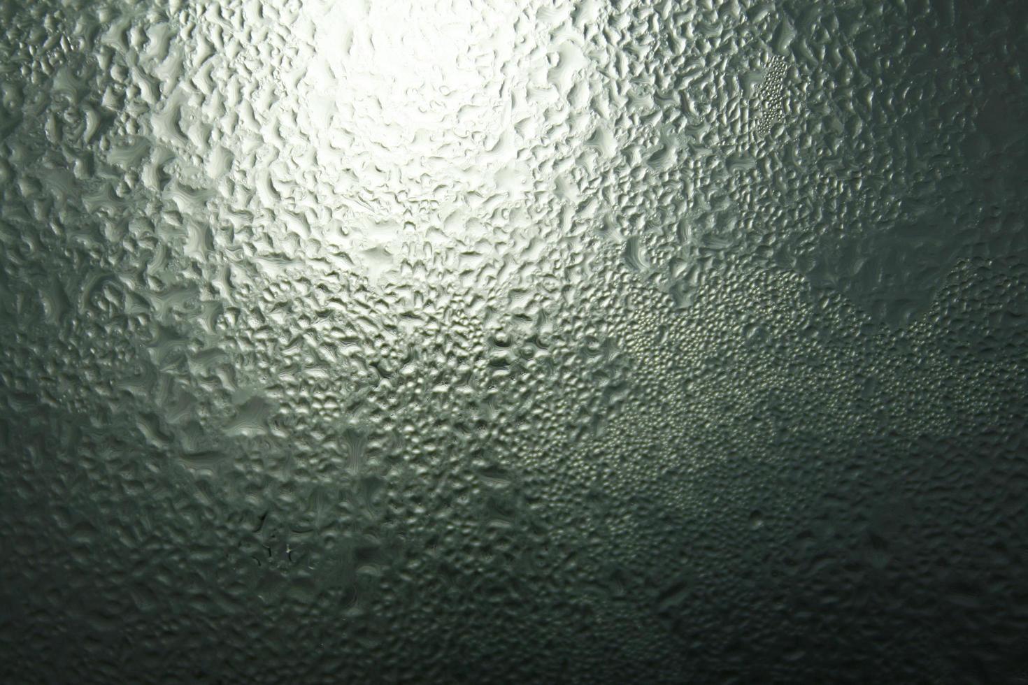 gotas de lluvia en una ventana en la oscuridad foto