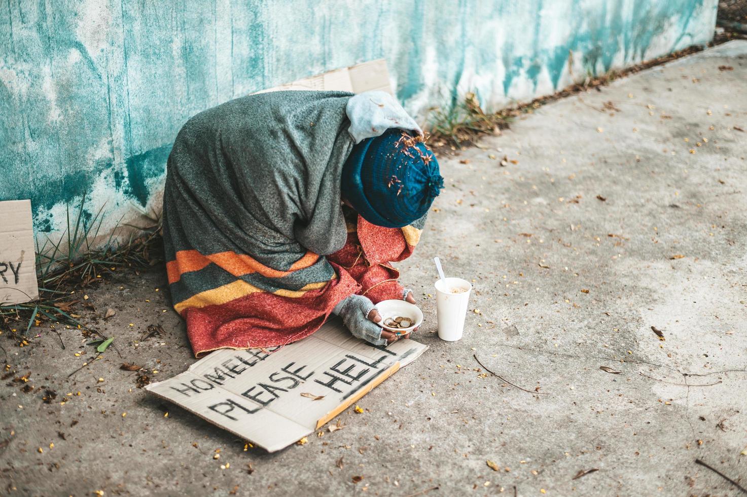 mendigos sentados en la calle con mensajes para personas sin hogar, por favor ayuden. foto