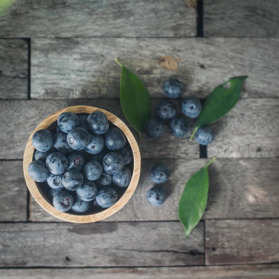 Fresh plums in a wooden bowl on old wooden background photo