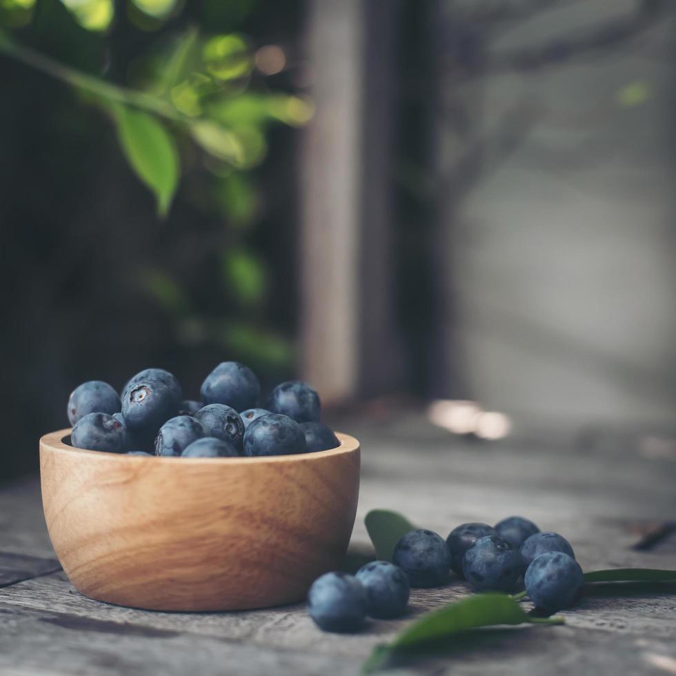 Fresh plums in a wooden bowl on old wooden background photo