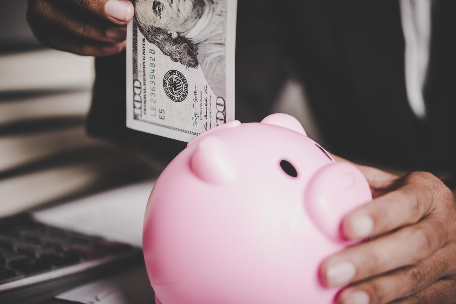 Woman putting euro banknote into a piggy bank photo