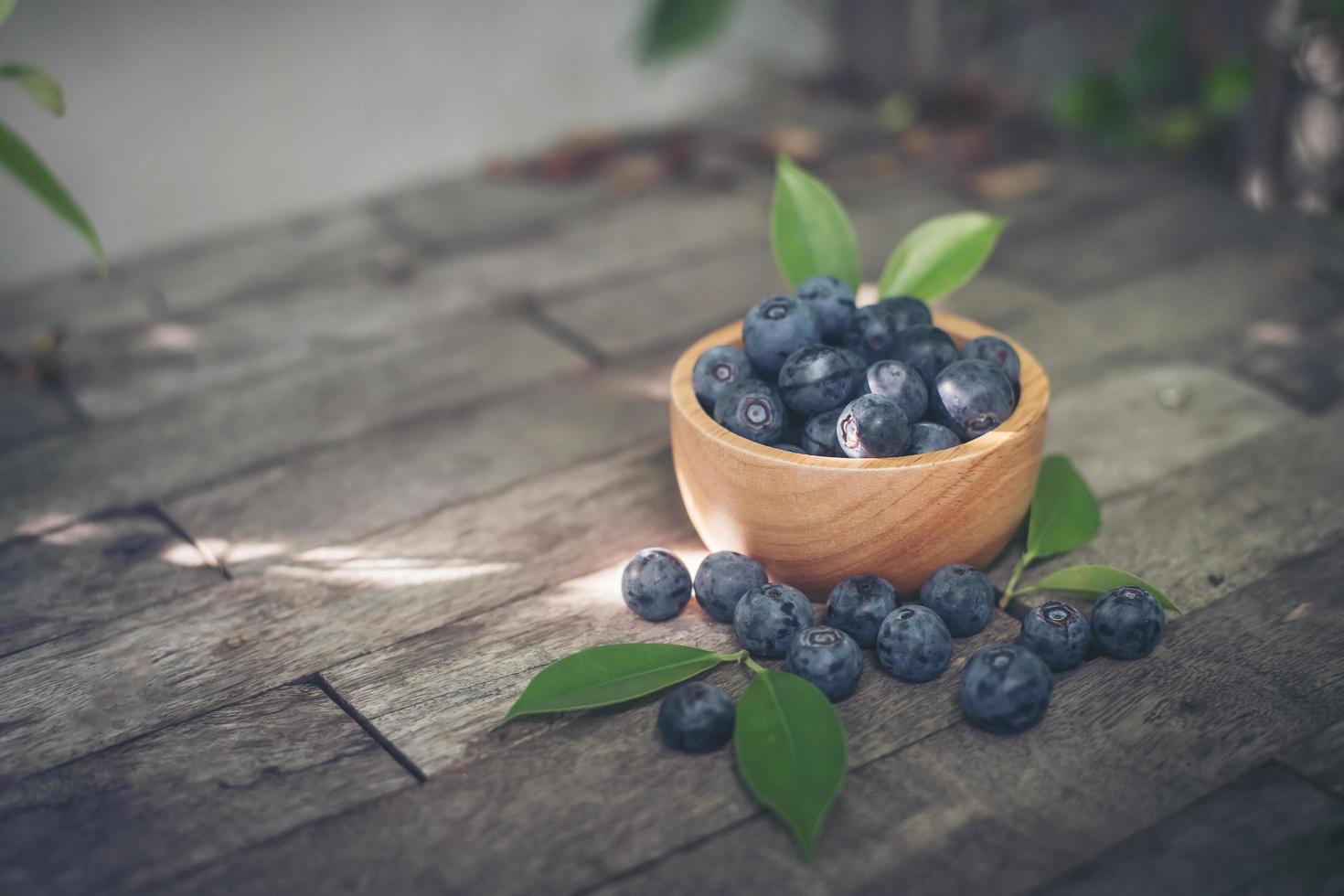 Fresh plums in a wooden bowl on old wooden background photo