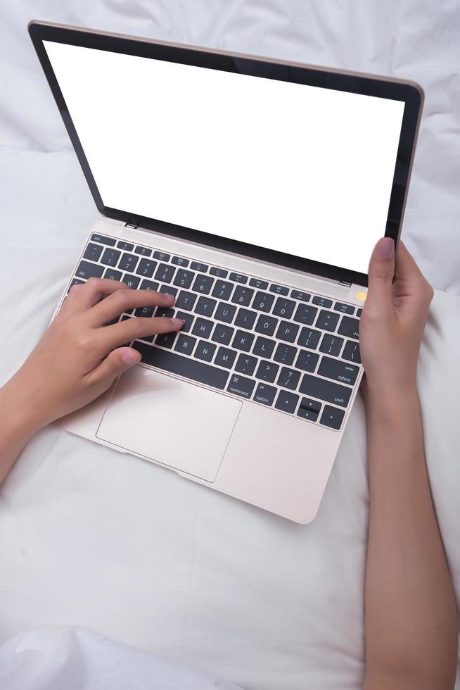 Mujer usando laptop mientras está sentado en la cama foto
