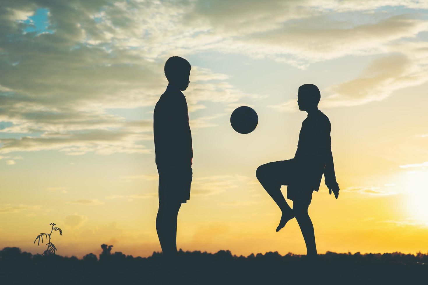 silueta de niños jugando al fútbol foto