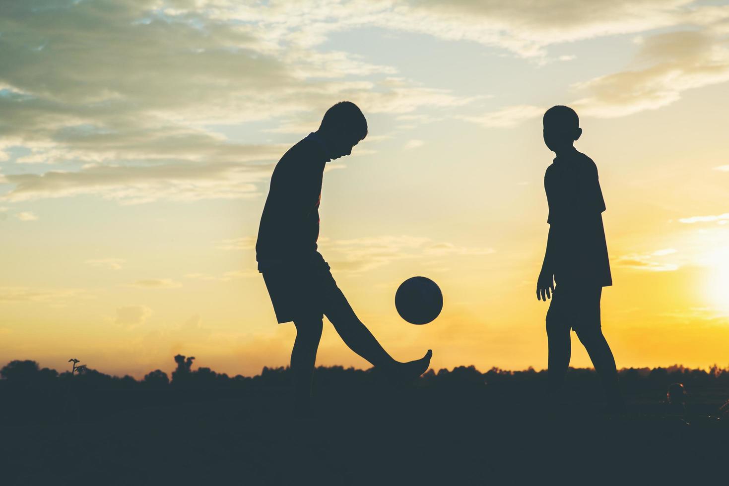 Silhouette of children playing soccer football photo
