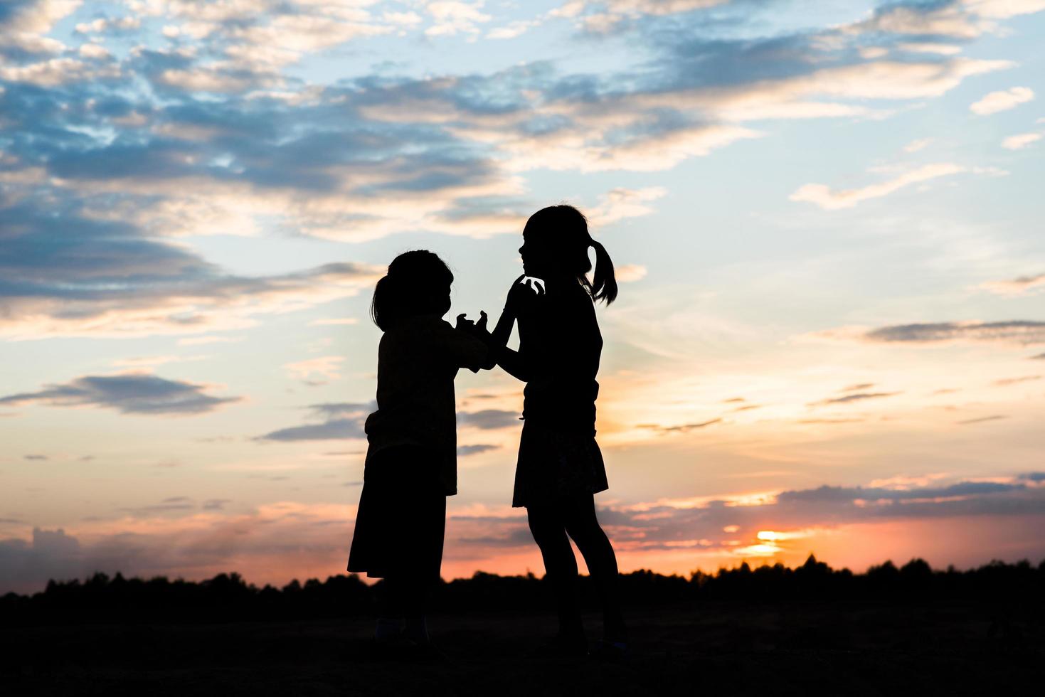 Sunset silhouette of children playing photo