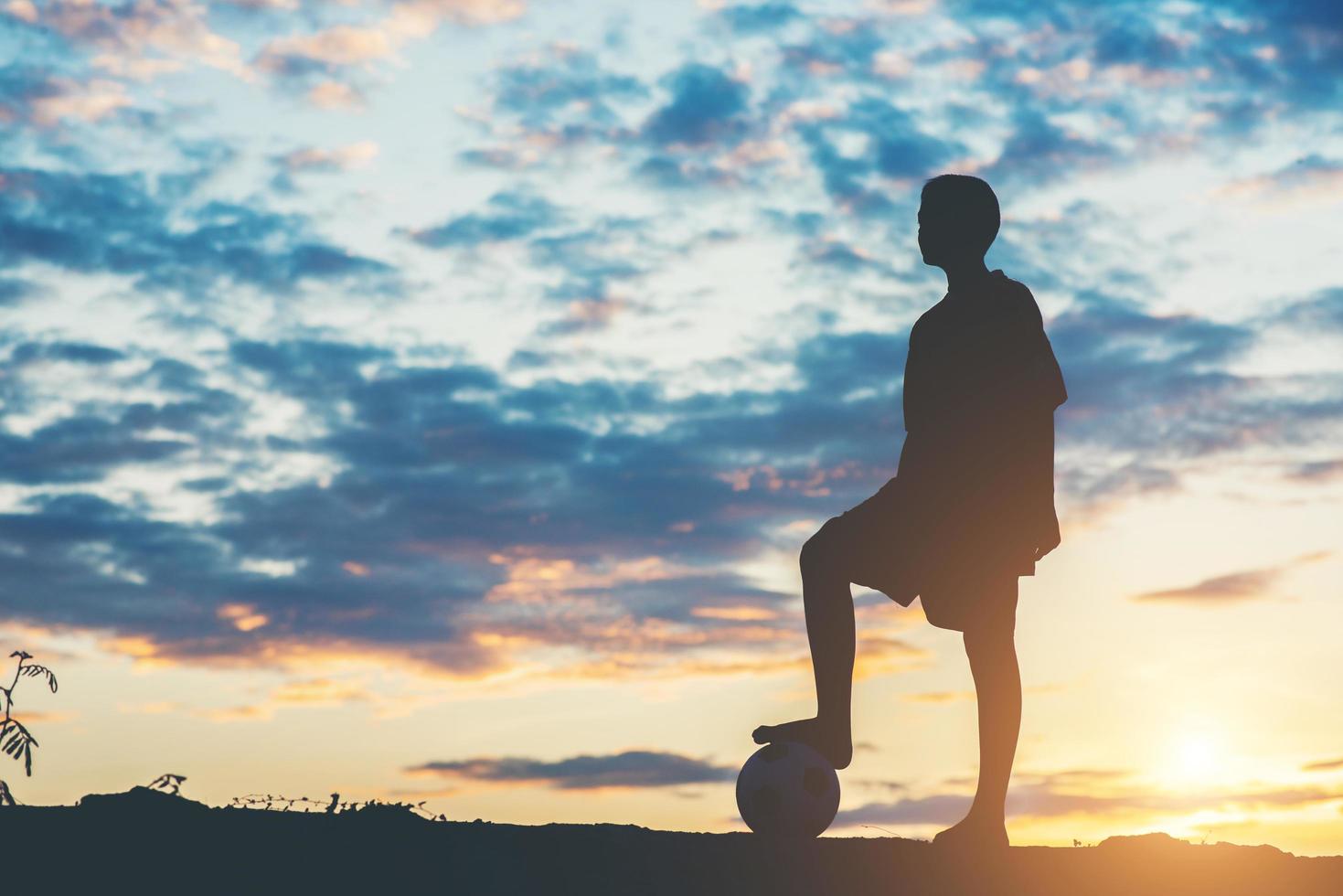 silueta de niños jugando al fútbol foto