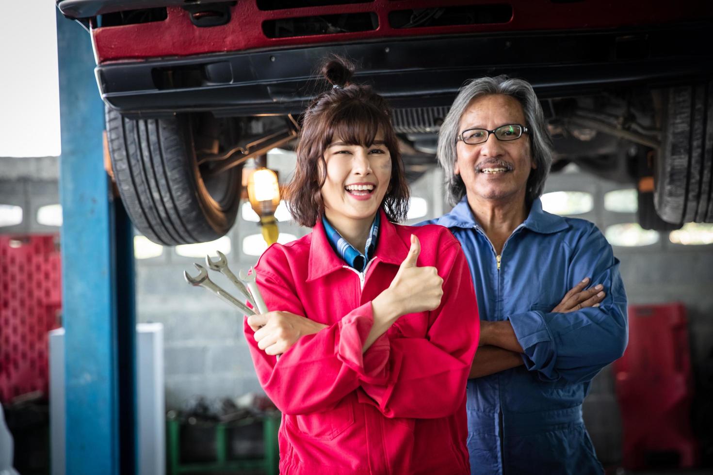 Portrait female technician and her supervisor in front of a car in a garage photo