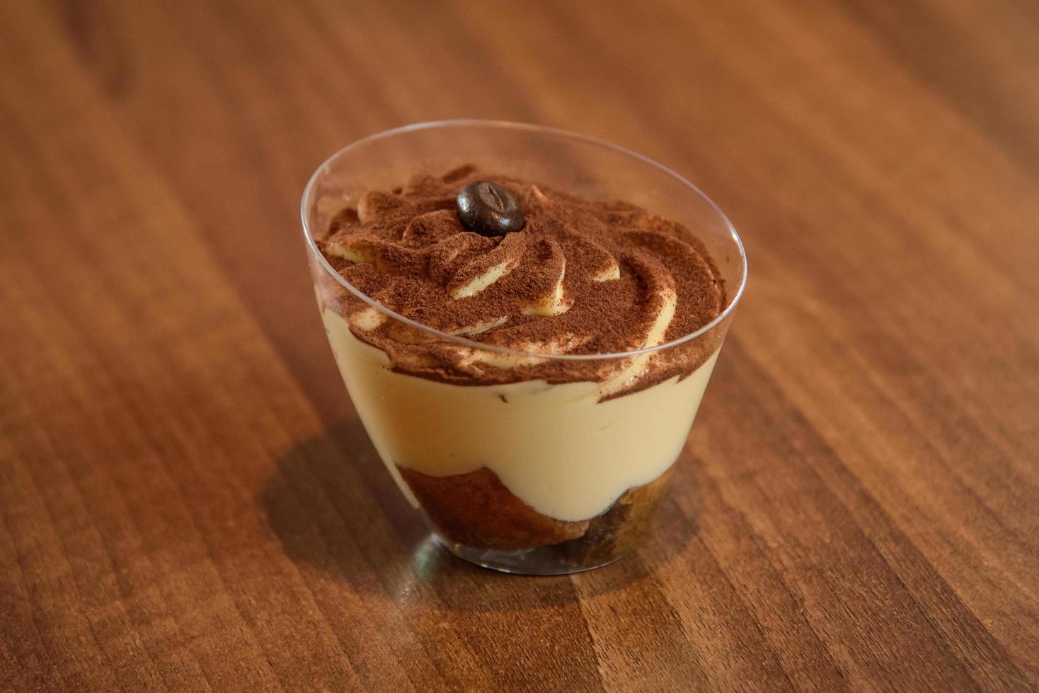 Tiramisú en vidrio sobre mesa vintage, postre tradicional italiano con sabor a café hecho de melindres y mascarpone foto