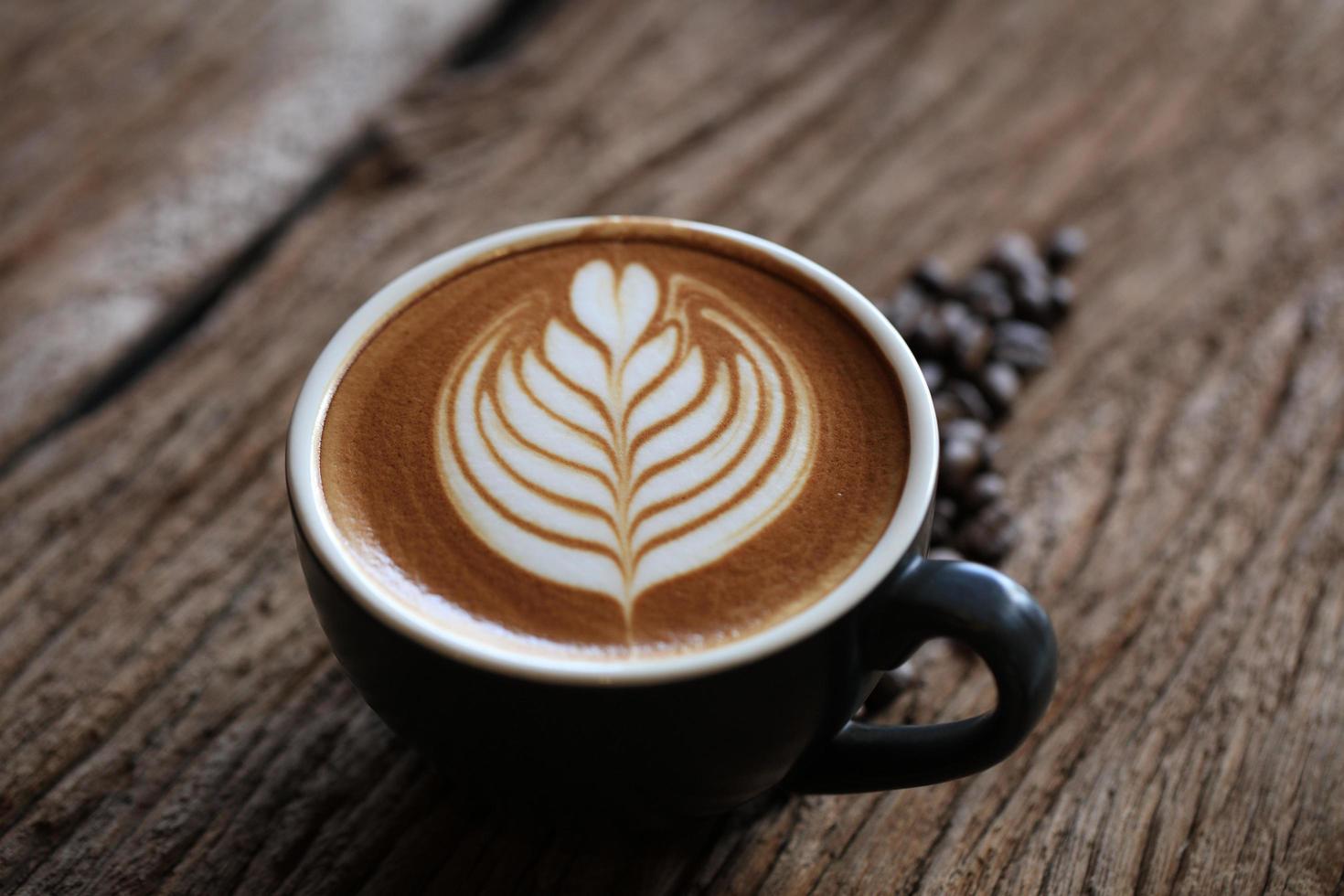 Hot cappuccino coffee with leave shaped art on a wooden table photo