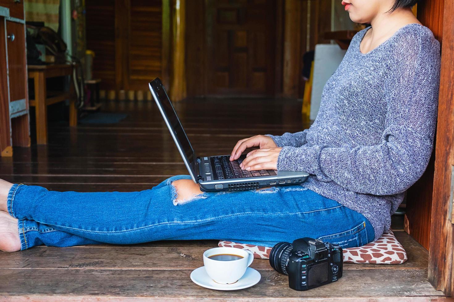 mujer sentada en el suelo con una computadora portátil y un café foto