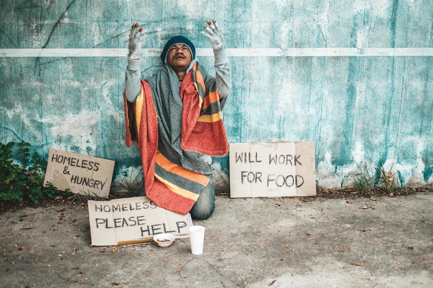 Man sits beside the street with a homeless message photo