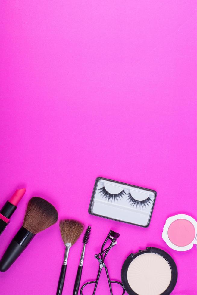 Top view of a collection of cosmetic beauty products on a pink background photo