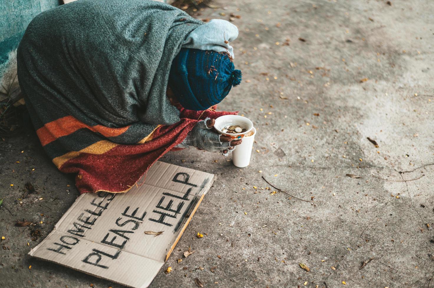 mendigos sentados en la calle con mensajes para personas sin hogar, por favor ayuden. foto