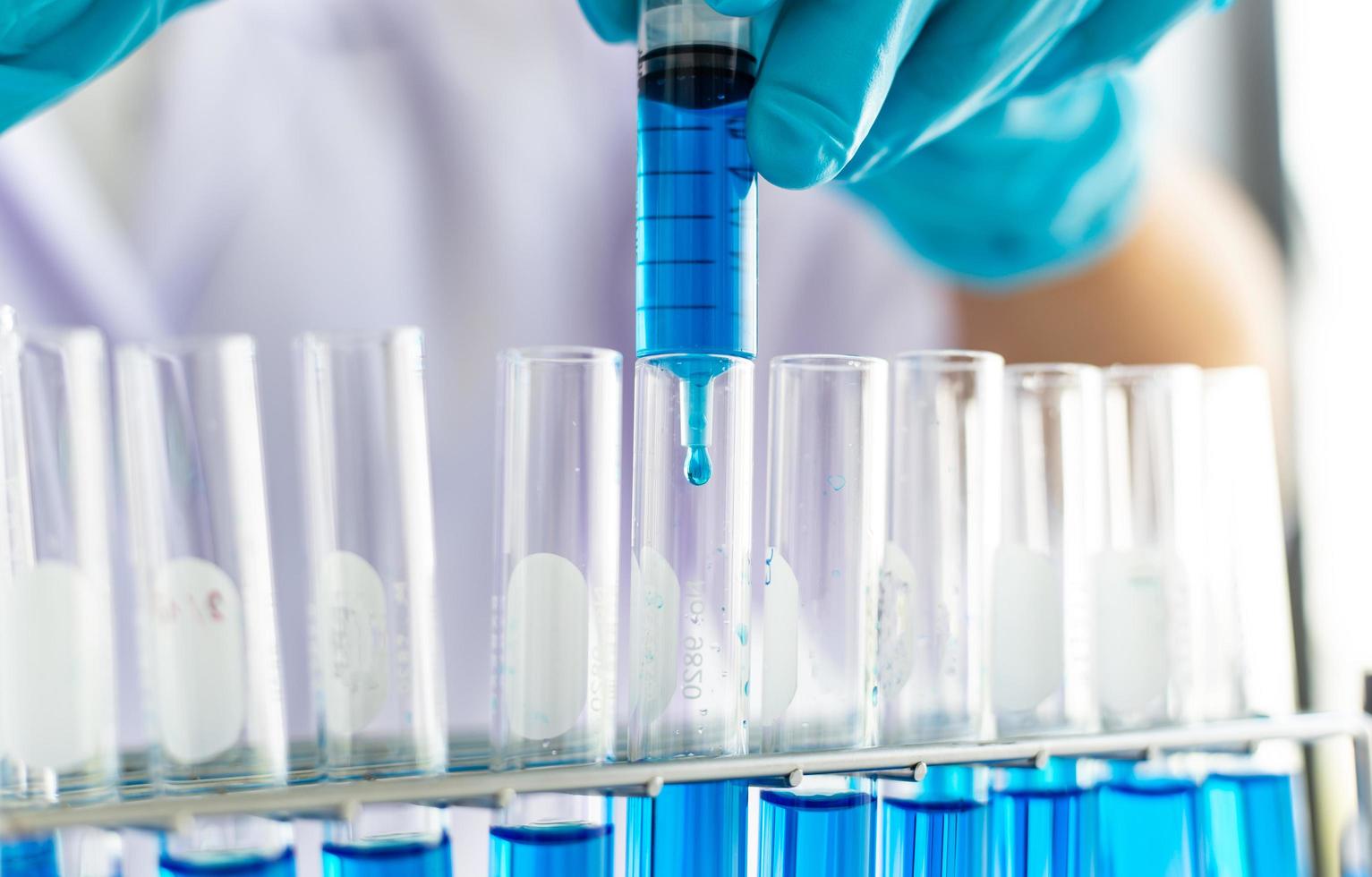 Scientist filling test tubes with syringe photo