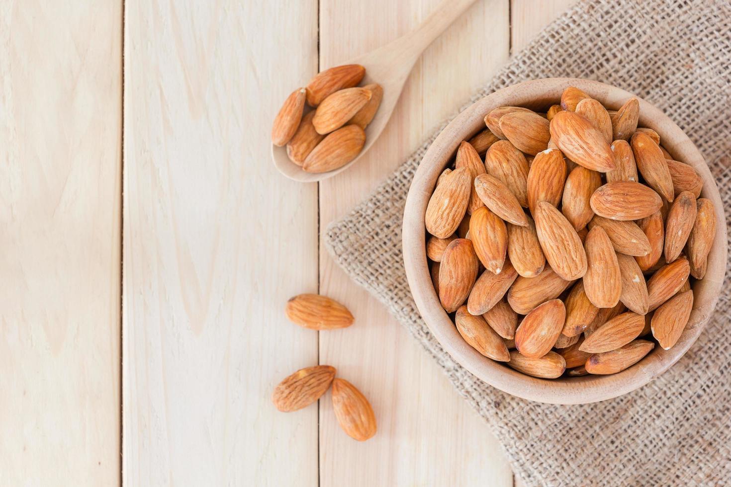 Almonds in wooden bowl on wooden table photo