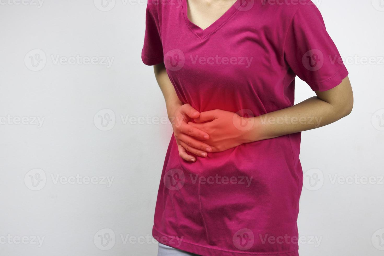 mujer con camisa rosa tiene dolor de estómago foto