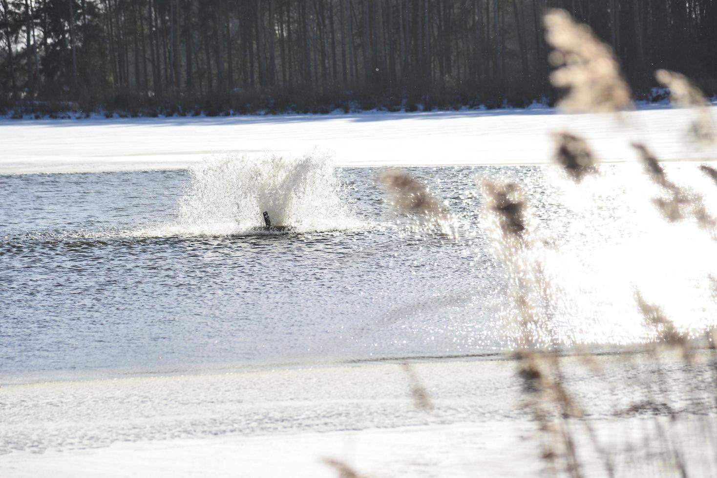 Partially frozen pond with an aeration fountain photo