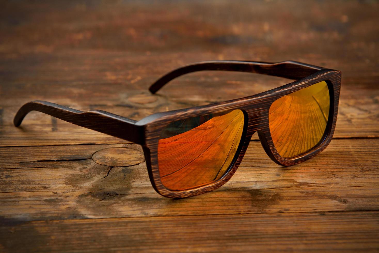Gafas de sol de madera marrón oscuro sobre superficie de madera foto