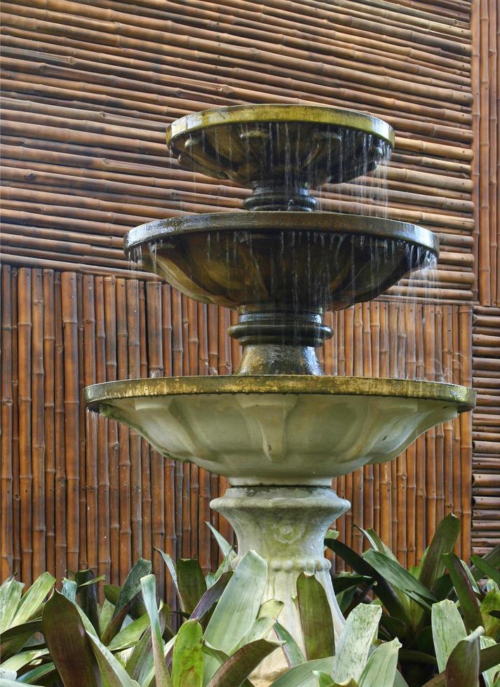 Fuente de agua contra una valla de bambú foto