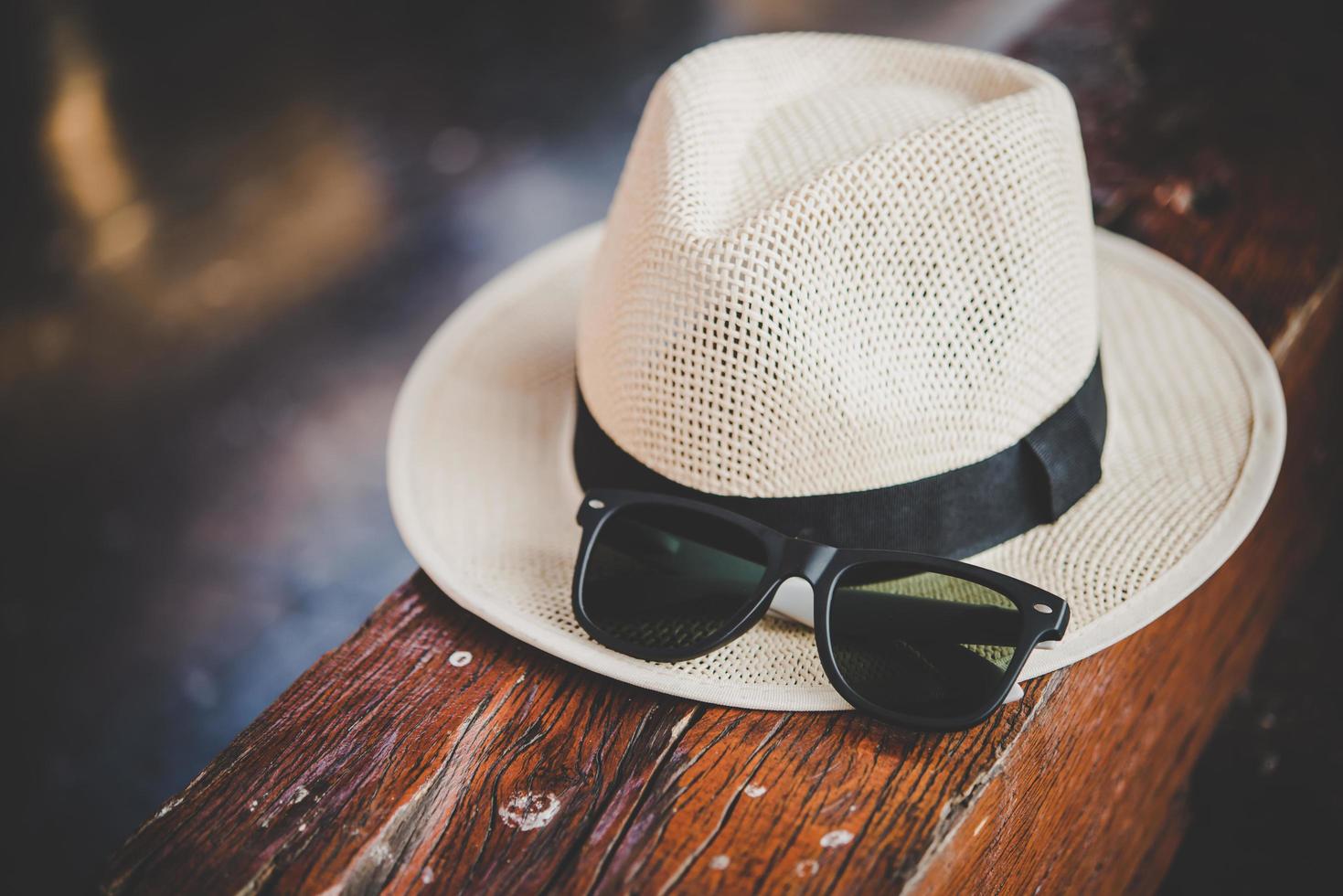 Hat and sunglasses on wooden bench at train station photo