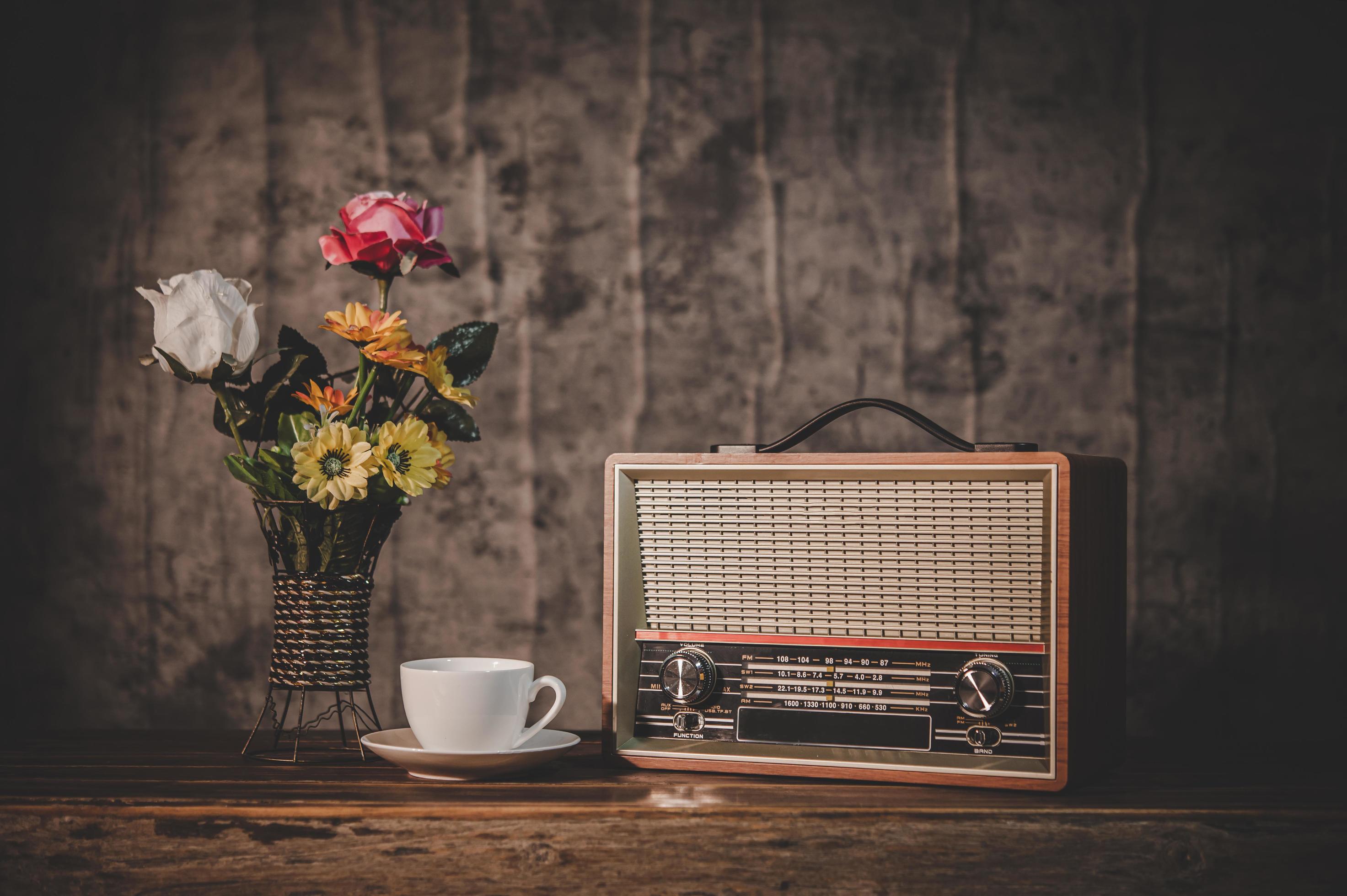 Retro radio receiver still life with coffee cup and flower vases