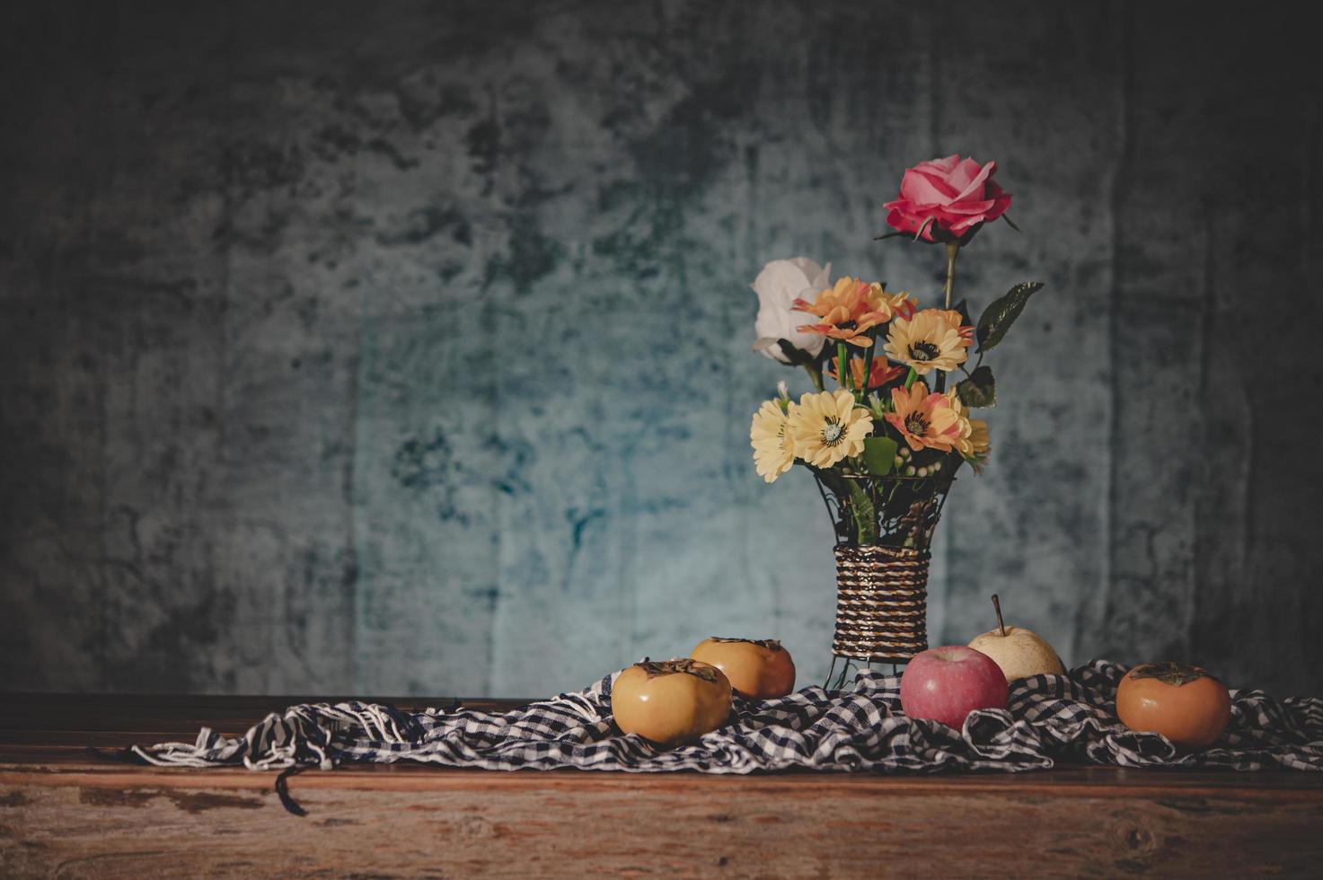 Still life with a vase of flowers and fruit on fabric photo