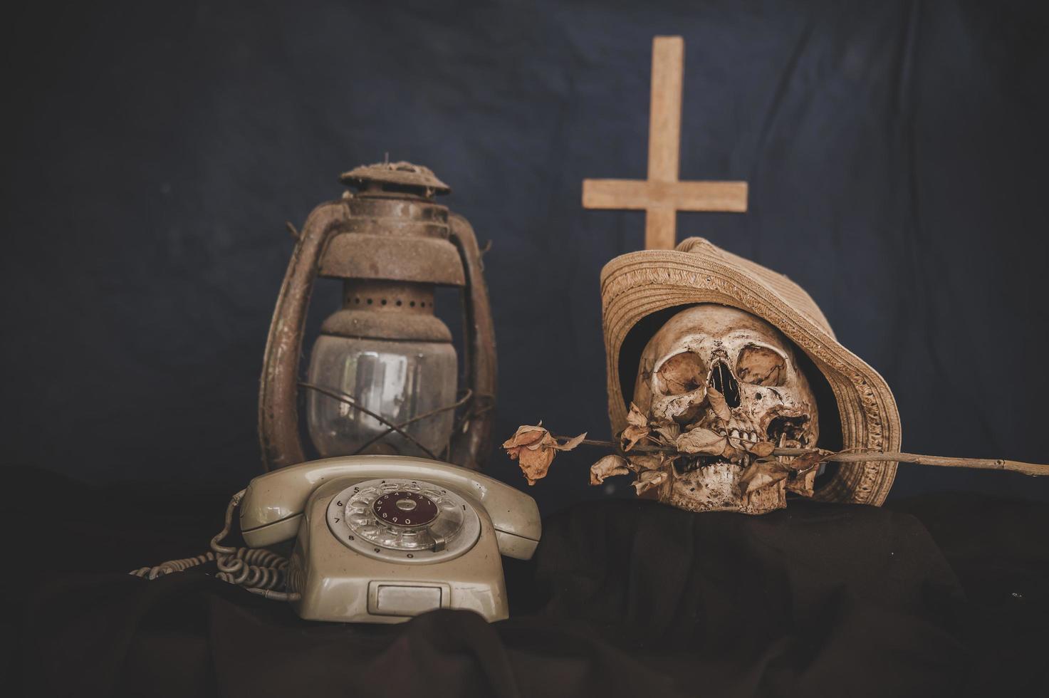 Retro style dial phone still life with a skull and an old lamp and cross photo