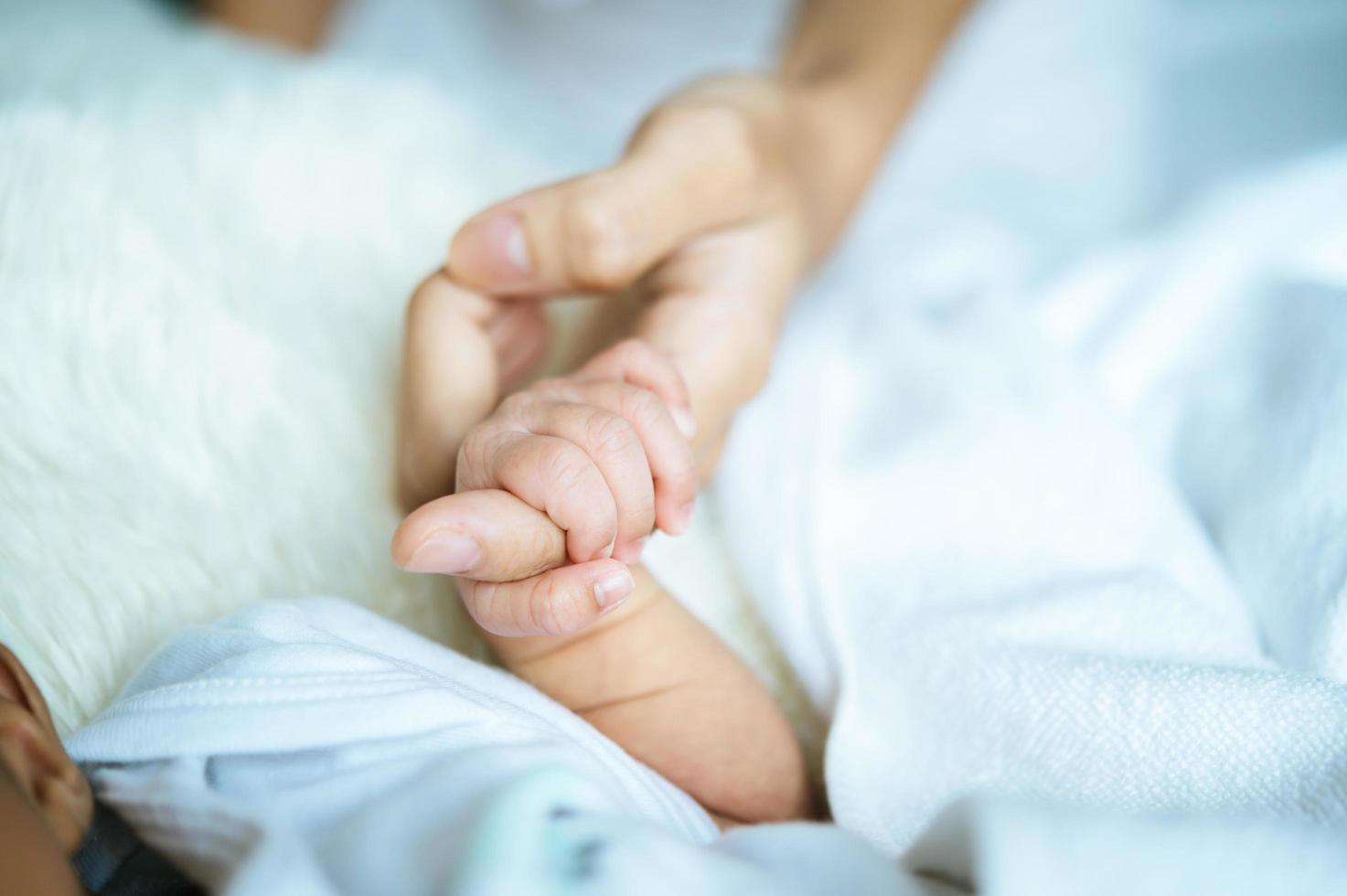 Newborn baby holding onto mom photo