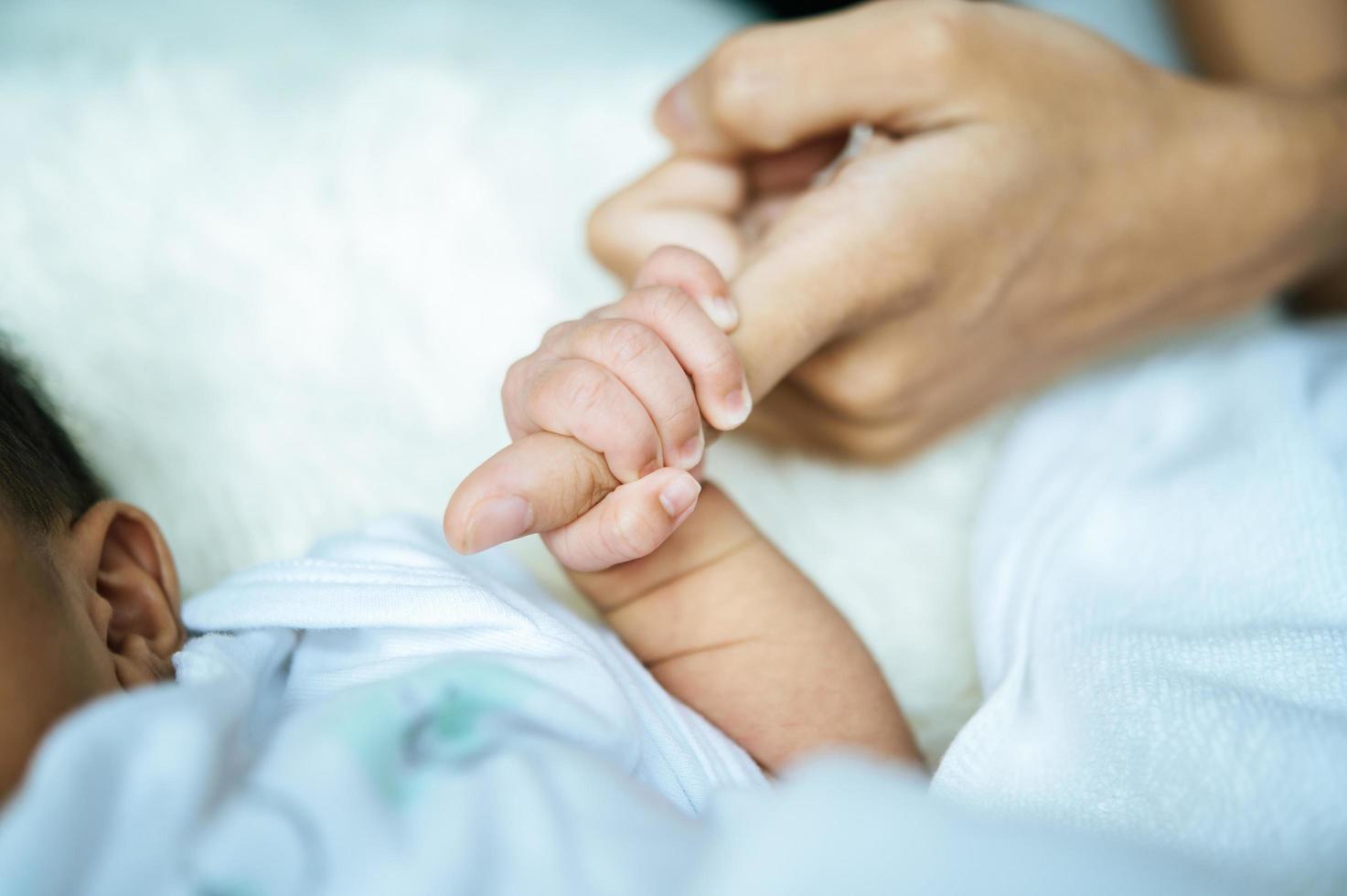 Newborn baby holding onto mom photo