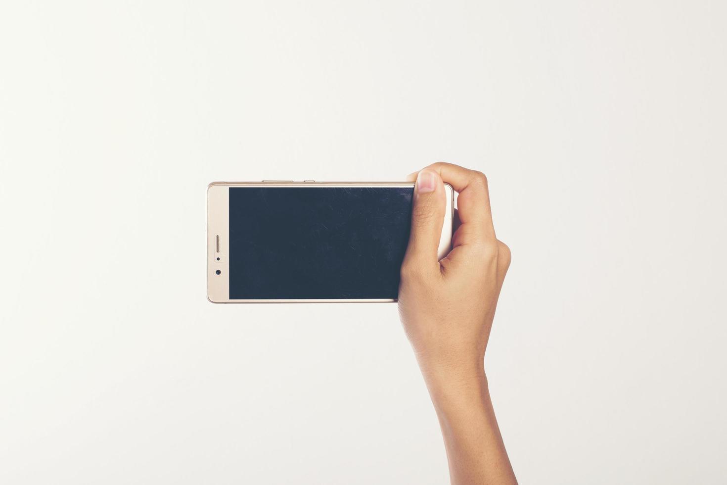 Close-up de una mujer sosteniendo un teléfono móvil aislado sobre fondo blanco. foto