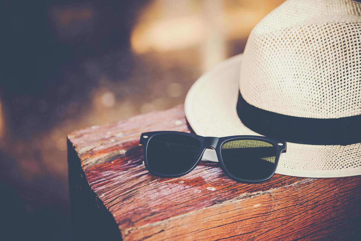 Hat and sunglasses on wooden bench at train station photo