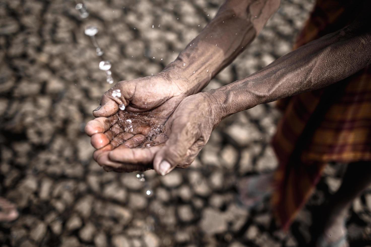 Elderly man shows open hands for water photo