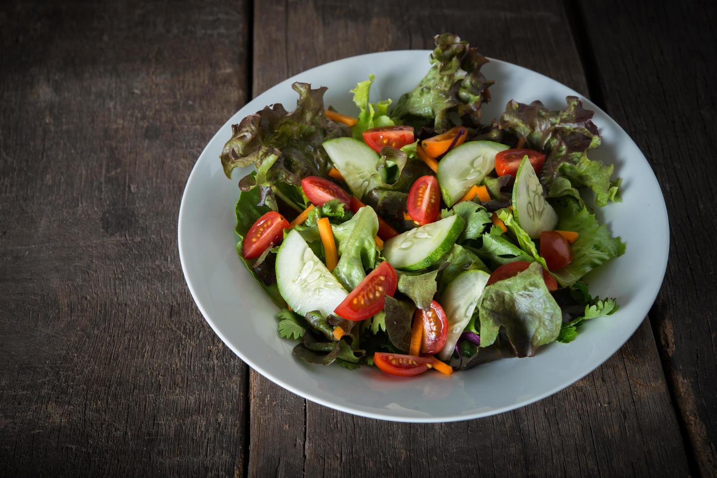 Fresh vegetable salad on wooden background photo