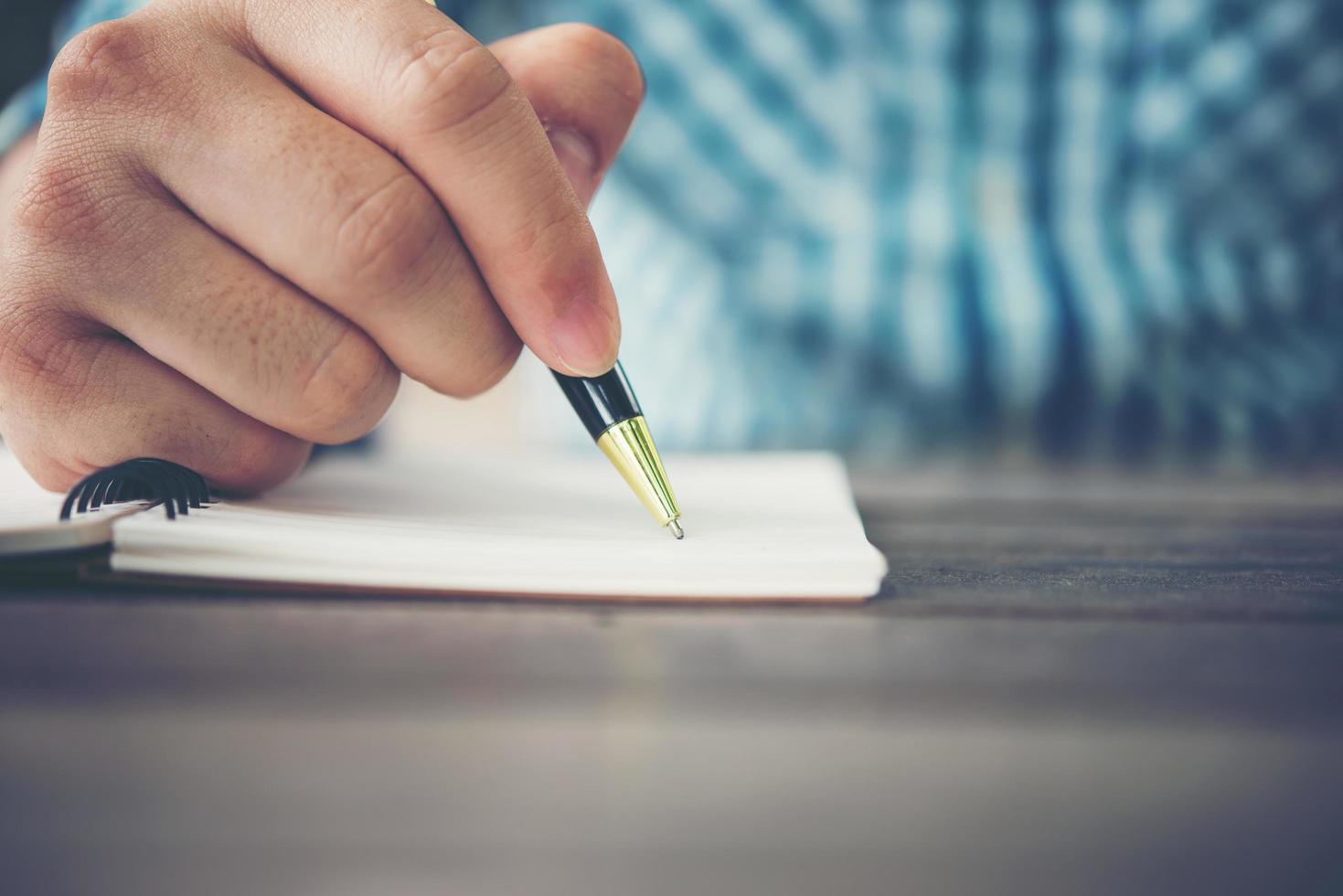Close-up de la mano del hombre escribiendo en un cuaderno con lápiz foto