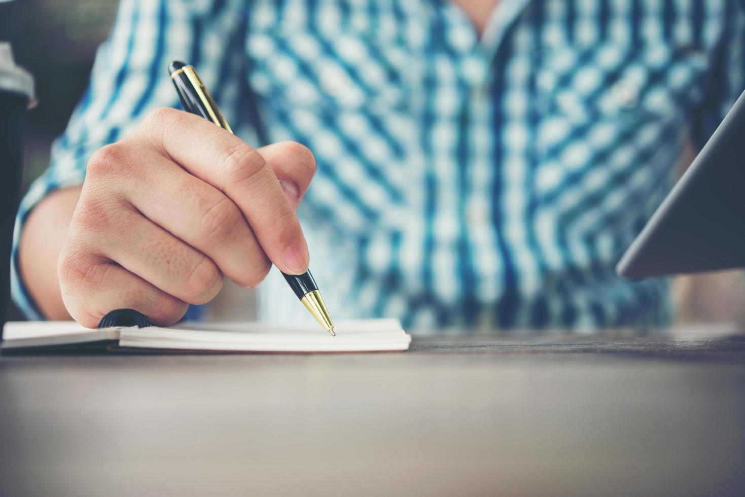 Close-up of man hand writing in notebook with pen photo