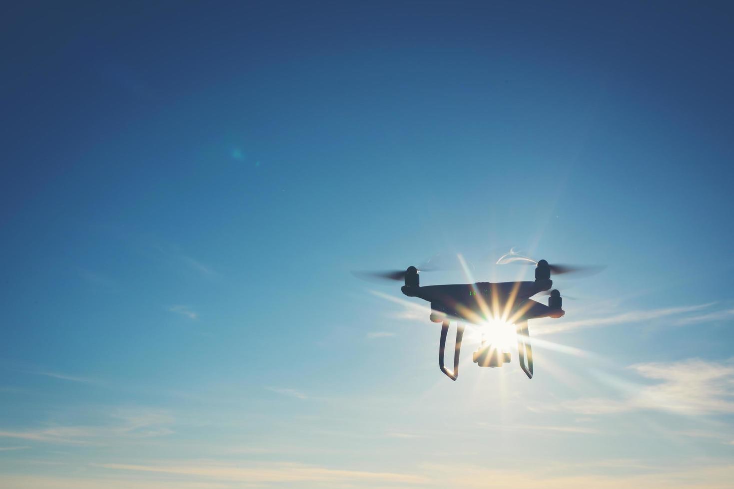 White drone hovering in a bright blue sky photo