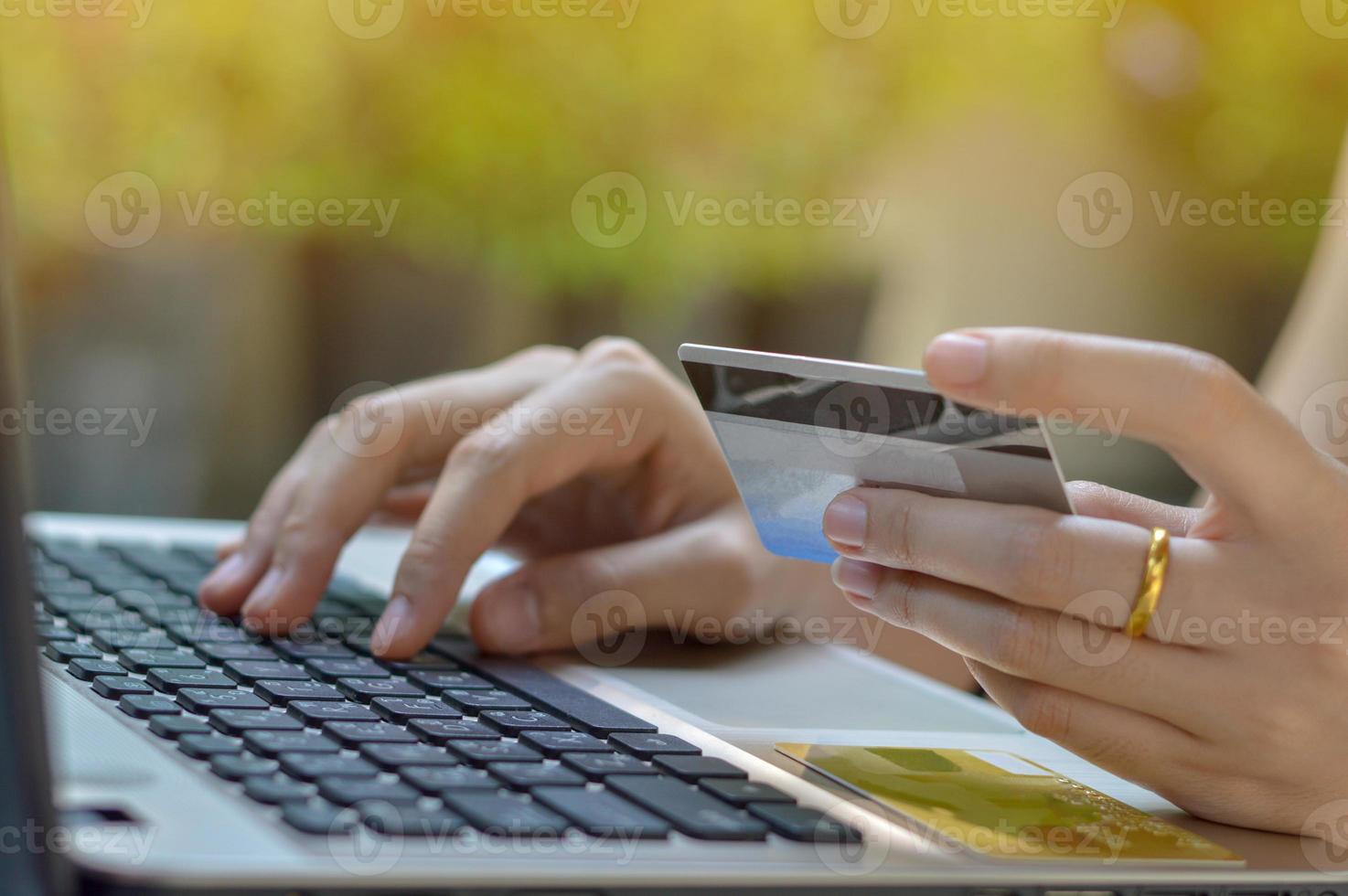 mano de niña sosteniendo tarjeta de crédito y usando laptop foto