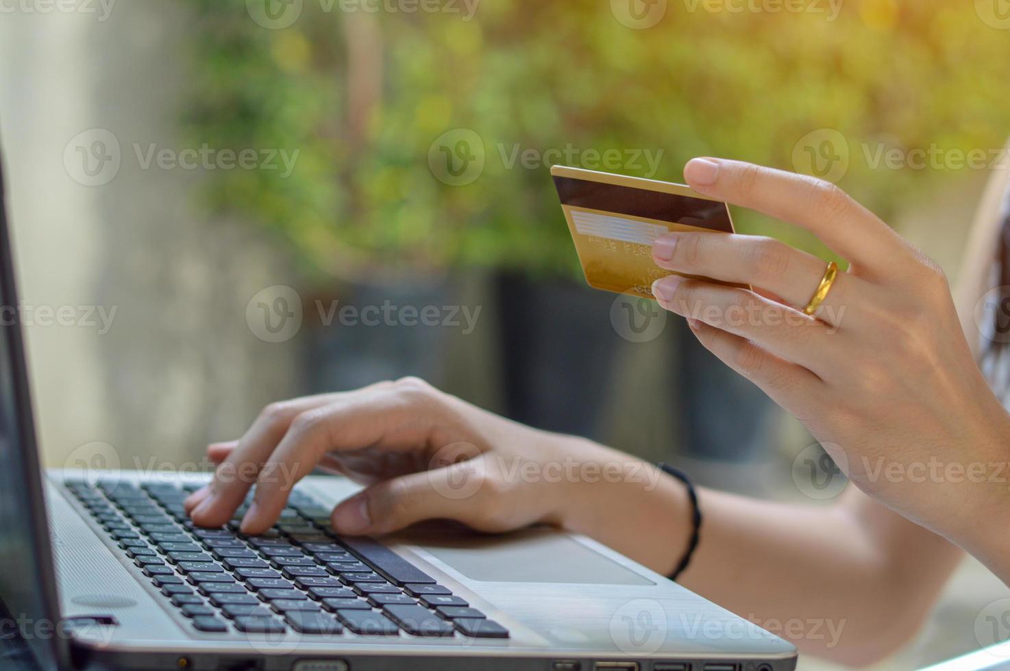 Young girl holding credit card and using laptop photo