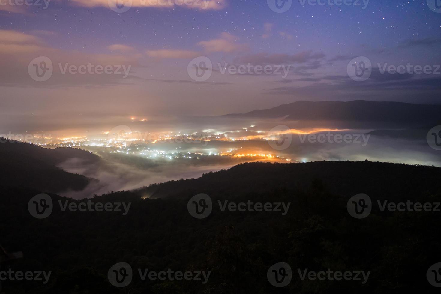 luces de la ciudad de niebla y montañas foto