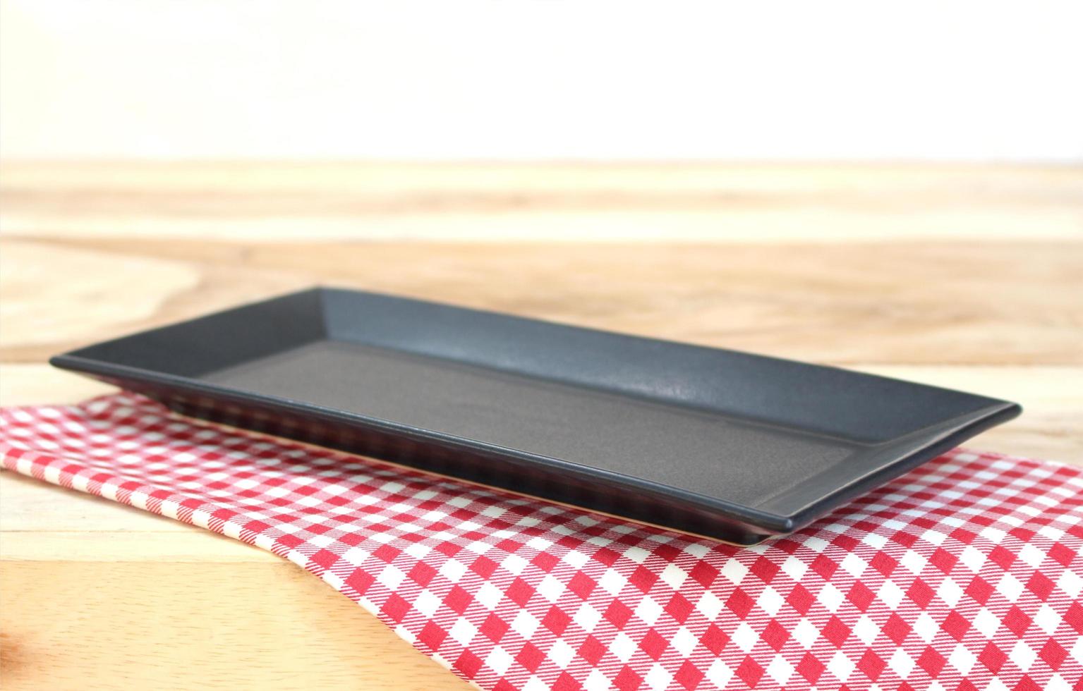 Black plate on checkered tablecloth on a table photo