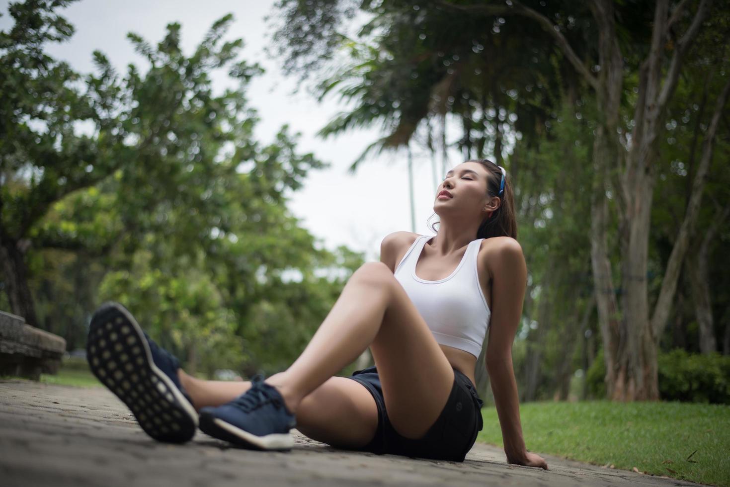 joven mujer deportiva se sienta en el parque después de un trote foto