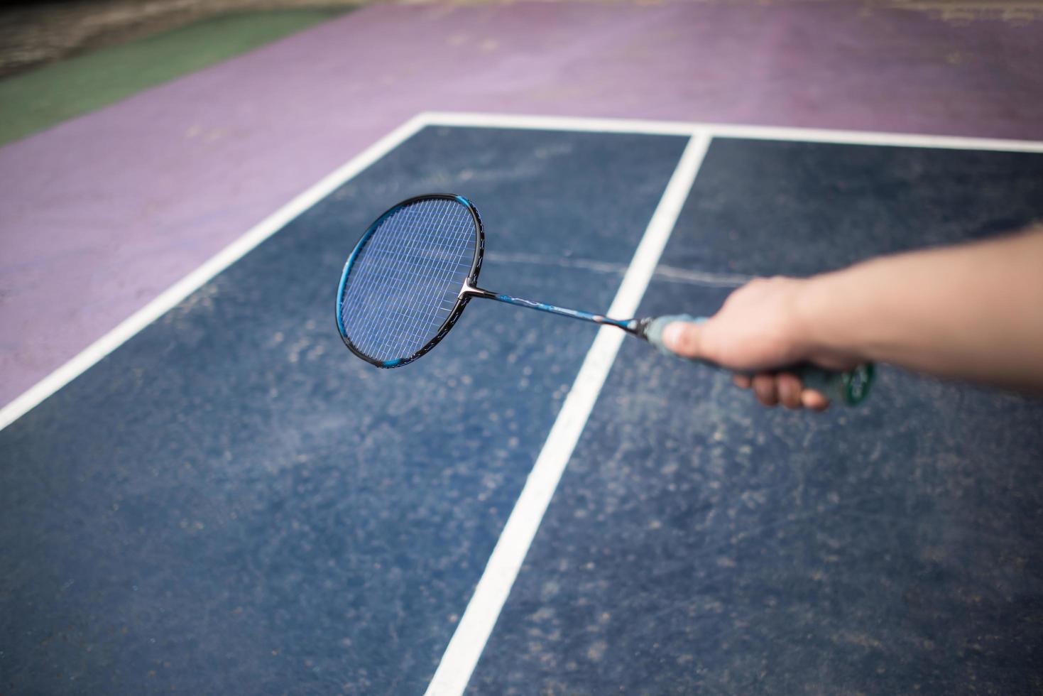 Young man playing badminton game outdoors photo