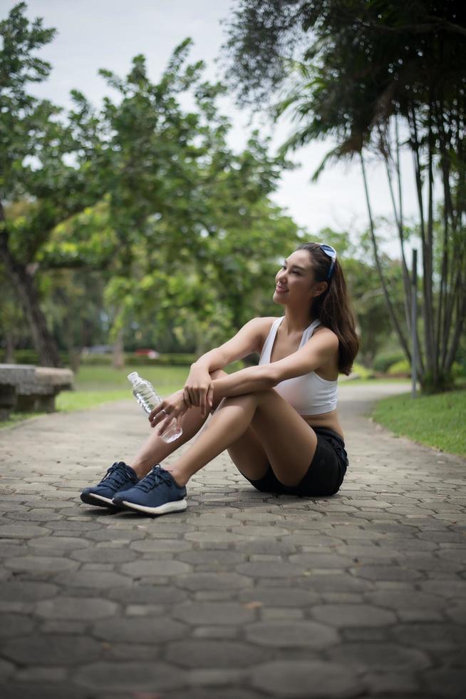 joven mujer deportiva se sienta en el parque después de un trote foto